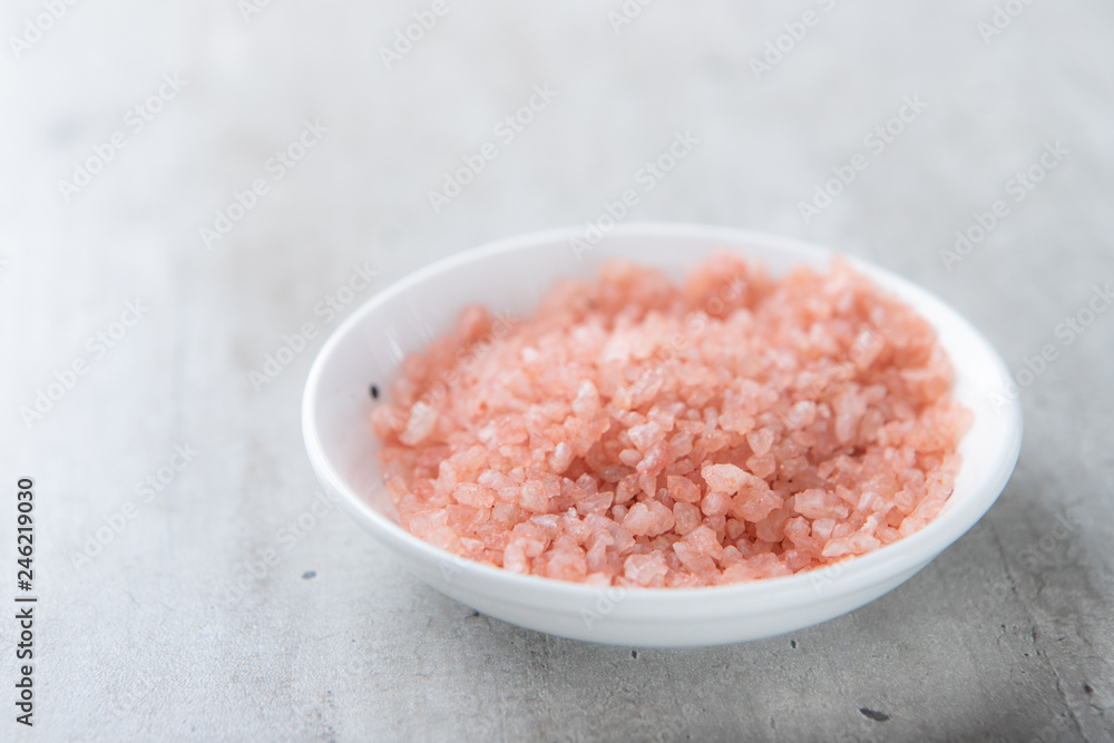 Himalayan pink salt in a white bowl on a gray background. Close up. Himalayan pink salt in a white bowl on a gray background. Close up.