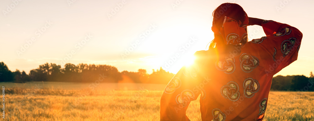 African woman in traditional clothes in a field of crops at sunset or sunrise