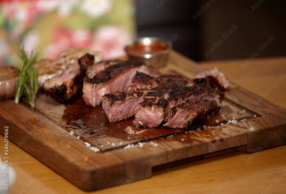 Grilled medium rare steak with coarse salt and rosemary on a wooden board