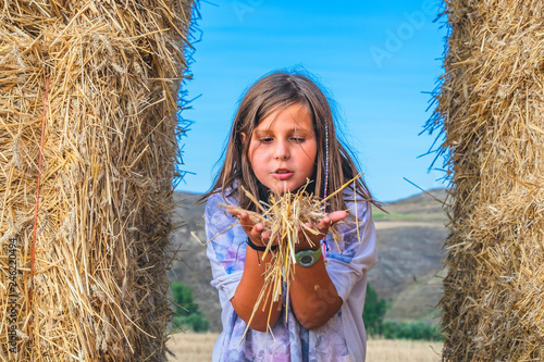 little girl playing alone in the field with straw bales and enjoying