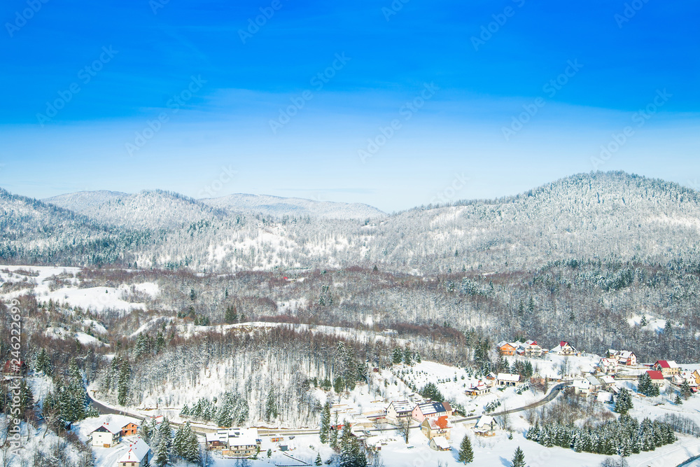 Croatian countryside landscape in winter, panorama of town of Lokve under snow in Gorski kotar, mountains in background