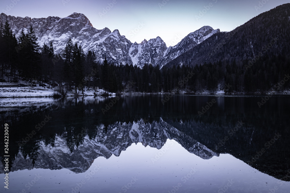 mirror reflection mountain in beautiful fusine lakes in julian alps in dusk blue hour, italy