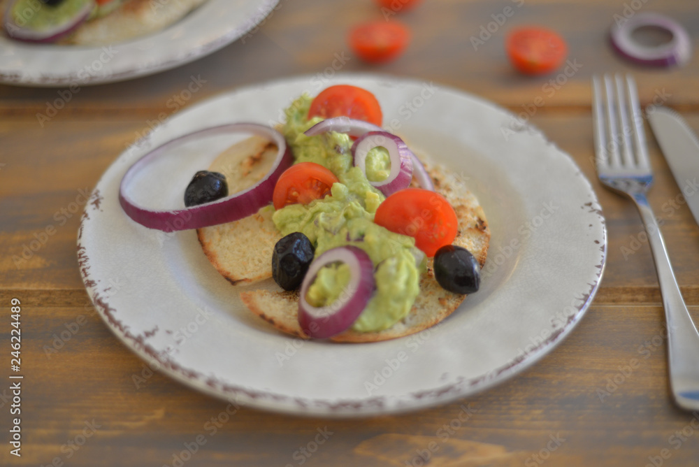 Healthy breakfast. Avocado salad with sherry tomatoes olives and onion on pita bread. On wooden table. flat lay top view copy space 
