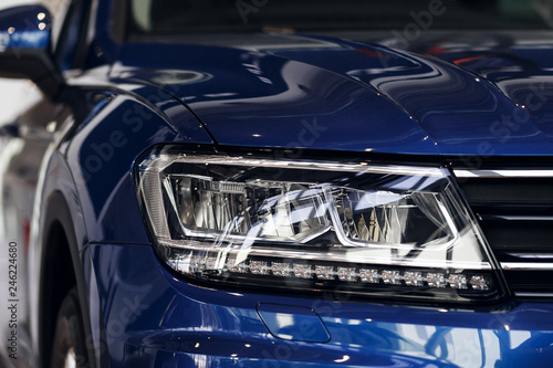 Closeup headlights of a modern blue color car. Detail on the front light of a car. Modern and expensive car concept. The car is in the showroom © svetlichniy_igor