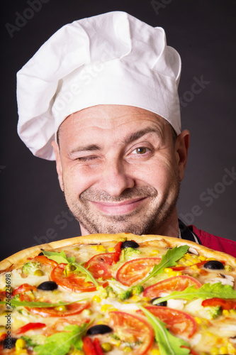 Portrait of happy attractive cook with a pizza