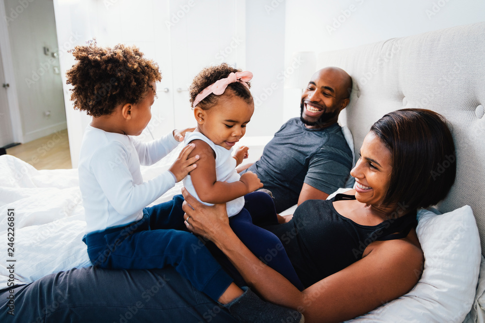 Smiling parents playing with children on bed at home Smiling parents playing with children on bed at home