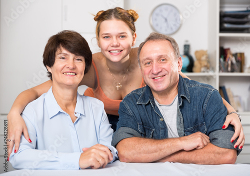 Smiling woman with her parents are posing at the table © JackF