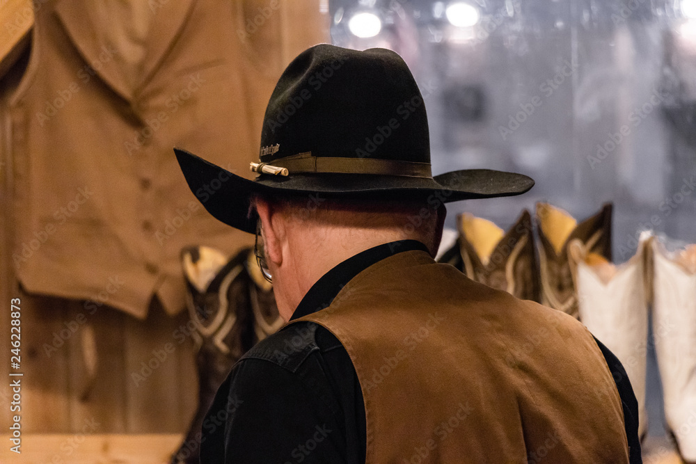 Old cowboy in western saloon. Black hat, leather jacket Old cowboy in western saloon. Black hat, leather jacket