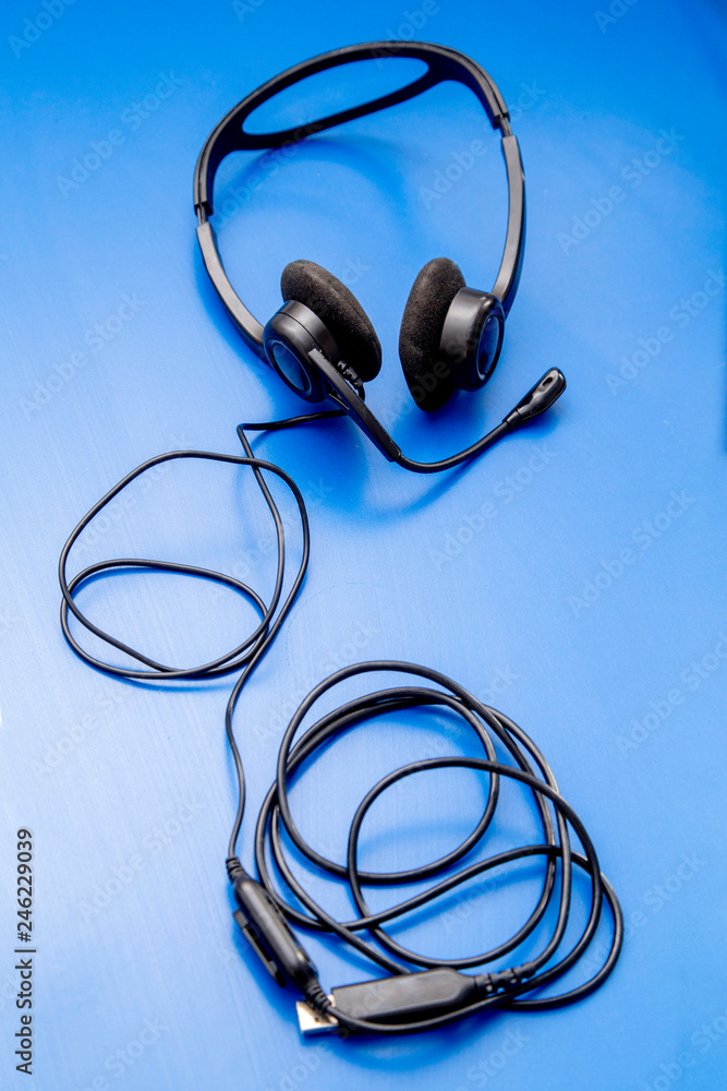 headphones with microphone and wire are on the blue table headphones with microphone and wire are on the blue table