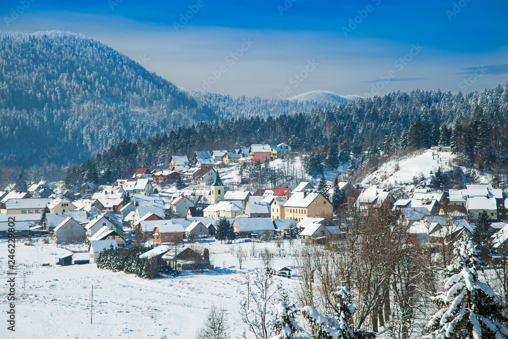 Panoramic view of town of Lokve under snow in Gorski kotar, mountains in background. Croatian countryside landscape in winter.