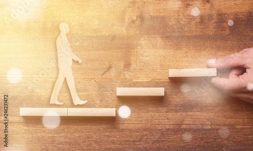 Success concept with wooden businessman climbing wooden block