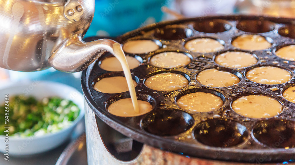 Khanom Khrok (coconut rice pancake), Traditional Thai Pudding Pancake Dessert, prepared by mixing rice flour, sugar, and coconut milk to form dough cooked in heating mantle (hot indented frying pan) - obrazy, fototapety, plakaty 