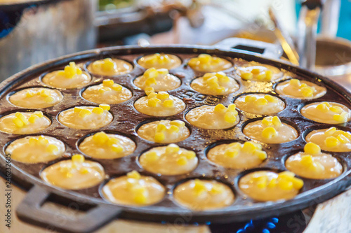 Khanom Khrok (coconut rice pancake), Traditional Thai Pudding Pancake Dessert, prepared by mixing rice flour, sugar, and coconut milk to form dough cooked in heating mantle (hot indented frying pan) photo