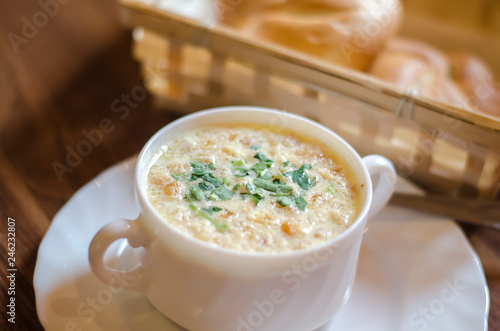 white cream soup in a white plate with crackers and herbs close-up