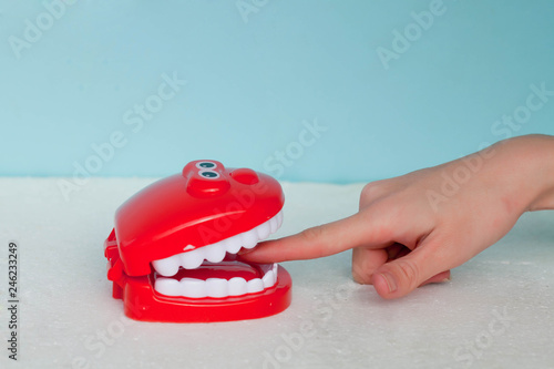 Some teeth biting a finger on a blue background. The finger in a mouth not of luggage, and that all hand will be bitten off, the Russian saying