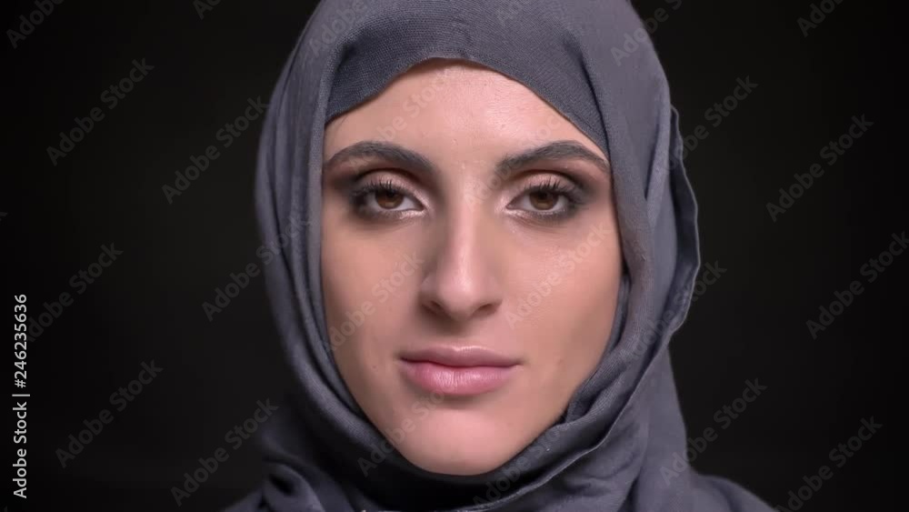 Portrait of beautiful muslim woman in hijab with bright make-up watching smilingly into camera on black background. Portrait of beautiful muslim woman in hijab with bright make-up watching smilingly into camera on black background.
