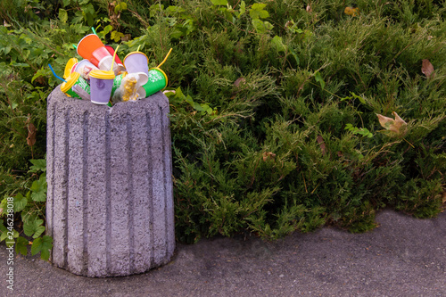 In the middle of a clean street in the park there is a complete trash tank