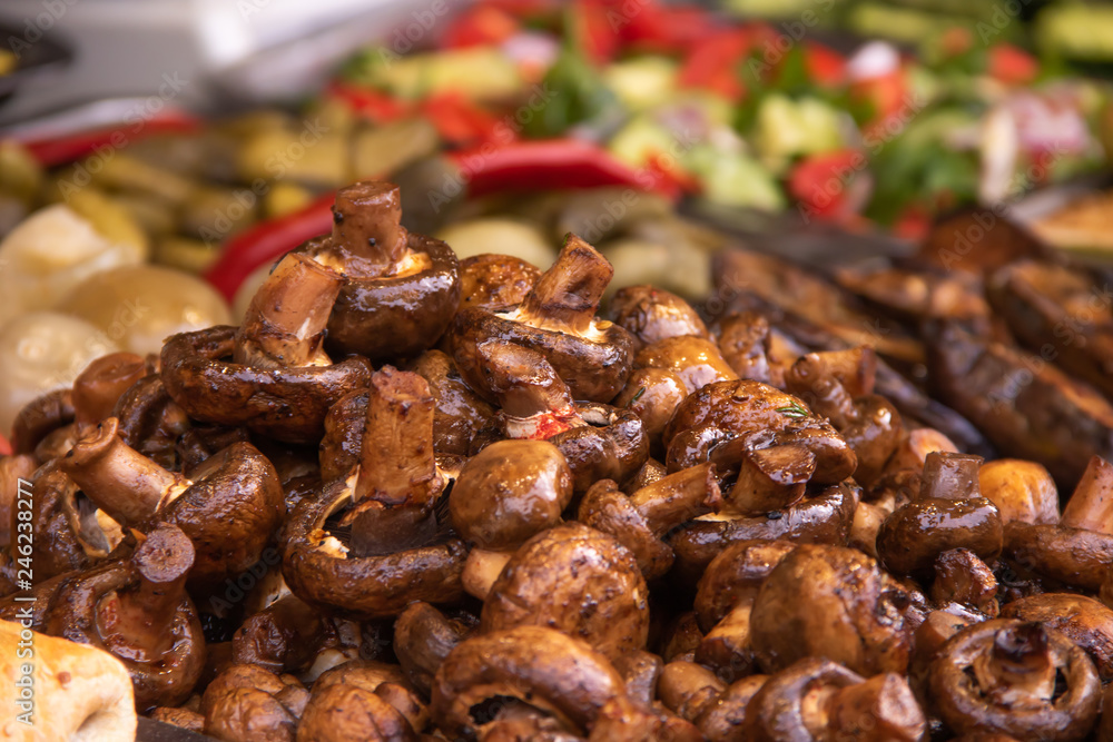 Fried Mushrooms Champignons on a plate on the background of a plate of chopped vegetables Fried Mushrooms Champignons on a plate on the background of a plate of chopped vegetables