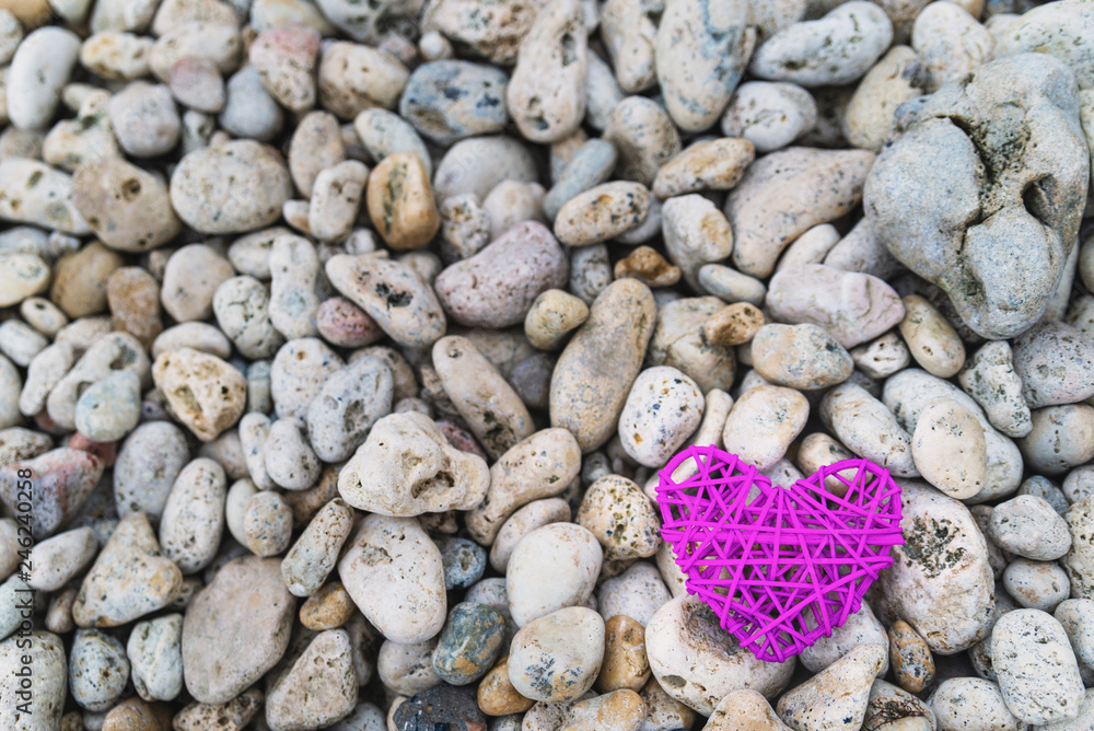 Purple knitted heart on a rocky beach Purple knitted heart on a rocky beach