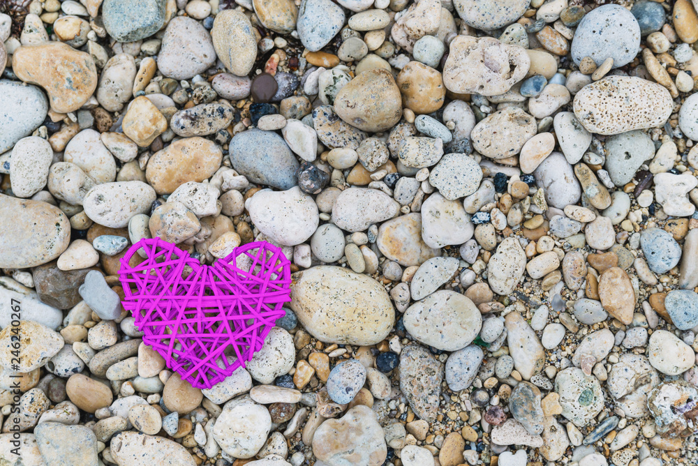 Purple knitted heart on a rocky beach Purple knitted heart on a rocky beach