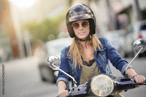 Φωτογραφία Attractive young woman riding scooter in city center