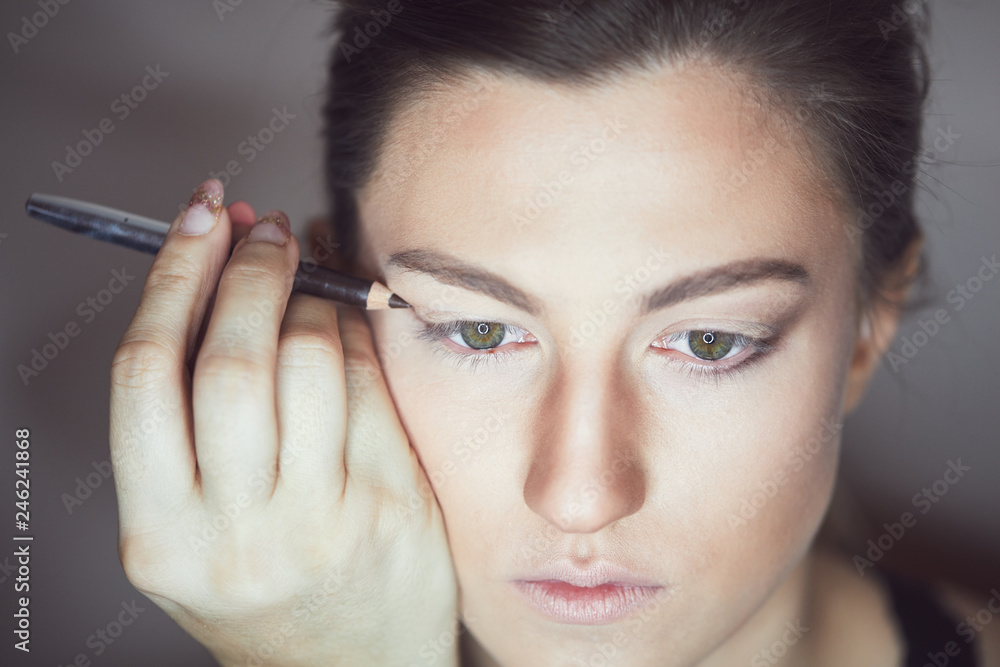Young beautiful woman applying make-up by make-up artist. Process of making makeup. Young beautiful woman applying make-up by make-up artist. Process of making makeup.