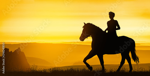 Girl rides on the hills under a golden sunset