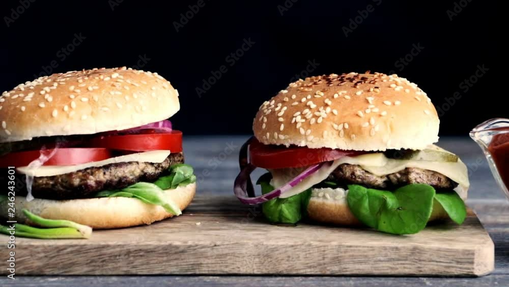Fresh burgers on wooden desk. Concept of fast food. Closeup. Slow pan. Fresh burgers on wooden desk. Concept of fast food. Closeup. Slow pan.