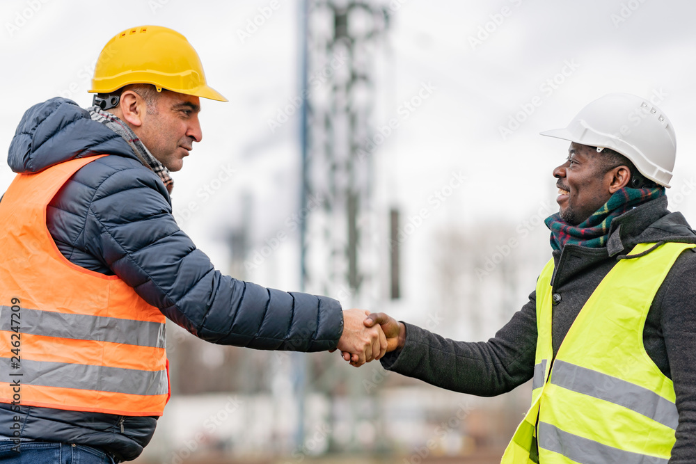 Successful handshake deal: multi-ethnic engineers reaching an agreement on construction site Successful handshake deal: multi-ethnic engineers reaching an agreement on construction site