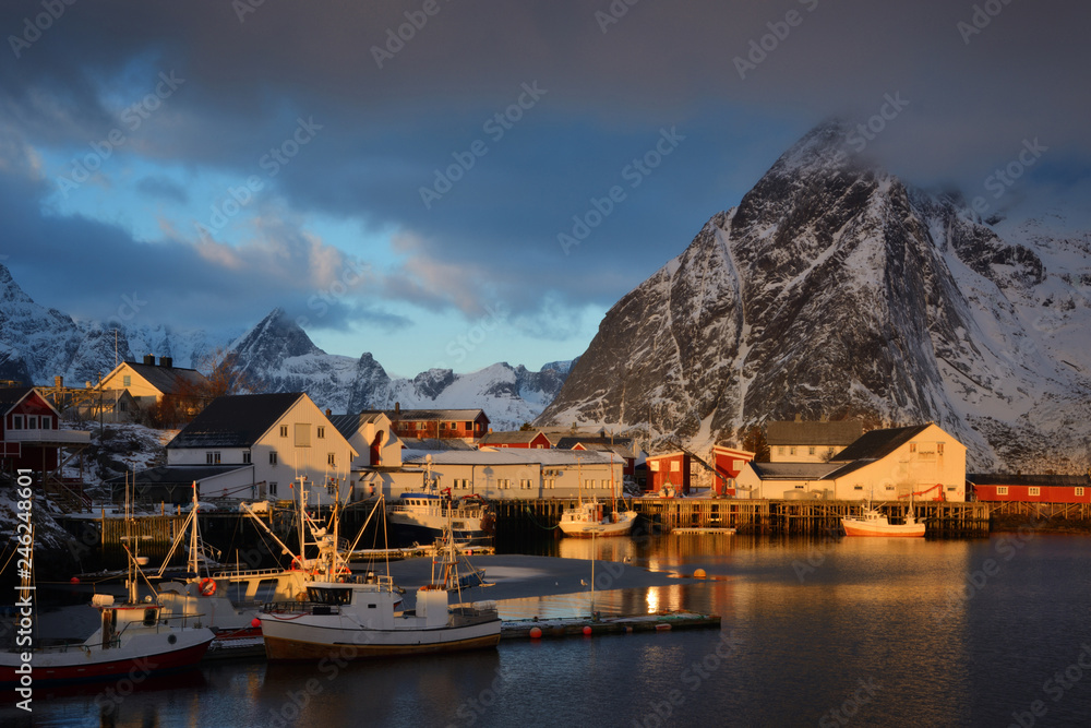 Hamnoy fishing village on Lofoten Islands at dawn. Norway with red rorbu houses in winter. A fishing boats at dawn in the fjord. Boats at the pier. Reine district