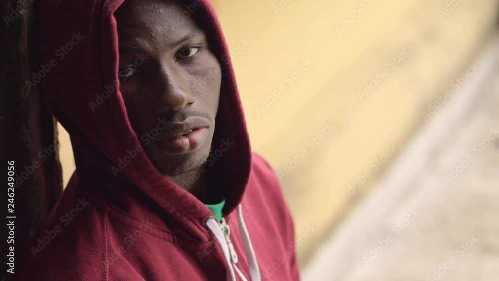 Sad pensive hooded young american african guy looking up and look at camera Sad pensive hooded young american african guy looking up and look at camera
