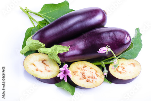 Fresh eggplants from flower beds, with leaves and flowers on white background. Creative layout of fresh eggplants. Concept of healthy eating. Vegetables isolated on white background.