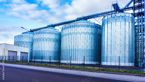Agricultural silos . Storage tanks for petroleum products . Equipment refinery . White tanks for petrol and oil in tank farm with blue sky . Tank farm . 