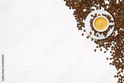 White wooden table with espresso cup and coffee beans. Flat lay.