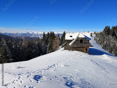 Sunny day in the mountains during winter time. Old house / cottage / house in the snow.