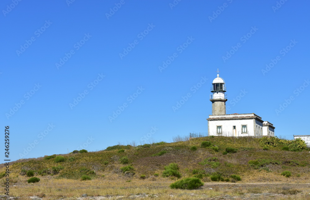 Old abandoned lighthouse on a hill with blue sky. Faro de Lariño, Carnota, Coruña Province, Spain.