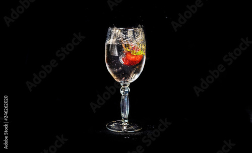 Strawberries fall in a glass of water