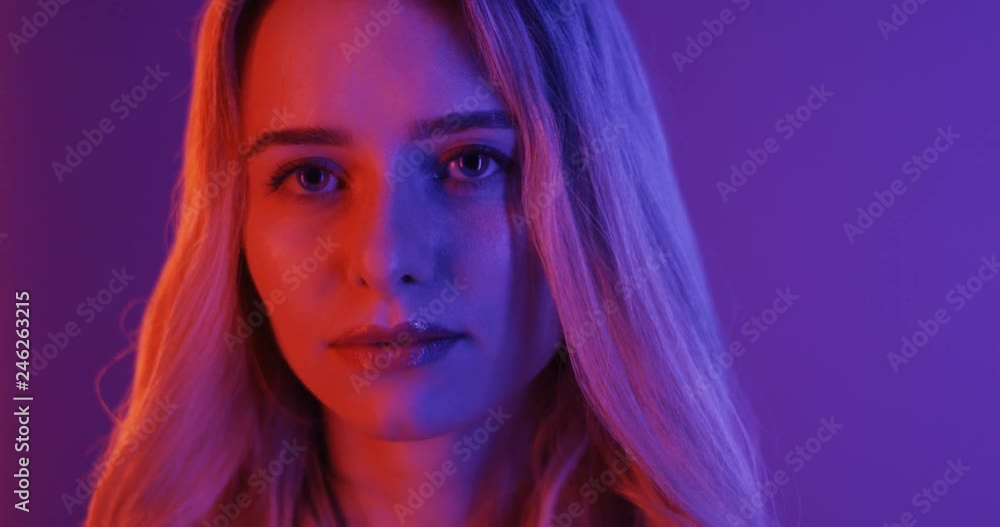 Close up of the good looking young blond woman face in the pink and blue neon lamps light. Portrait. Close up of the good looking young blond woman face in the pink and blue neon lamps light. Portrait.