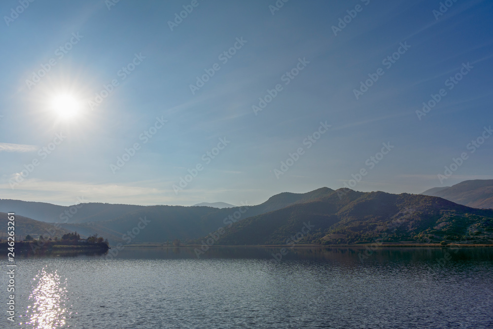 Lake Zazari with a background of the mountains, the sun, the houses and the cars