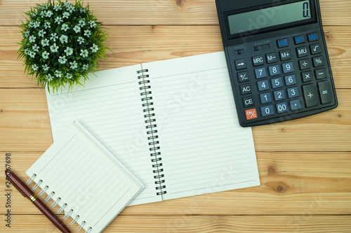 Office supplies or office work essential tools items on wooden desk in workplace, pen with notebook and calculator, top view