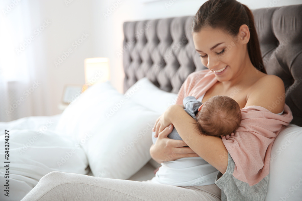 Young woman breastfeeding her baby in bedroom - obrazy, fototapety, plakaty 