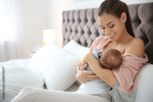 Young woman breastfeeding her baby in bedroom photo
