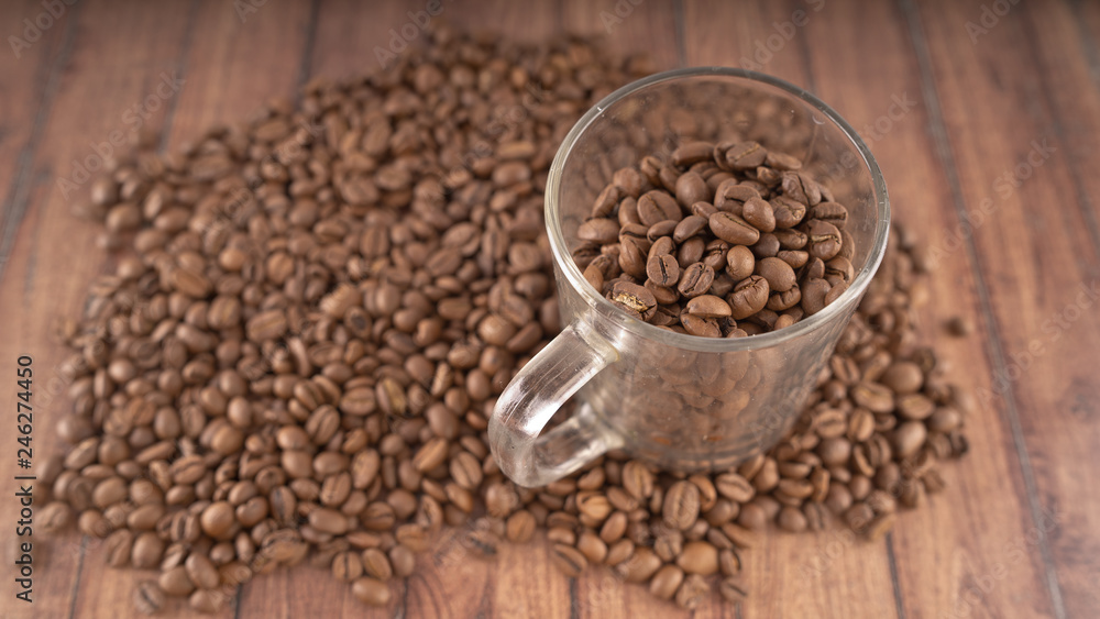 Coffee cup filled with coffee beans over a brown background Coffee cup filled with coffee beans over a brown background