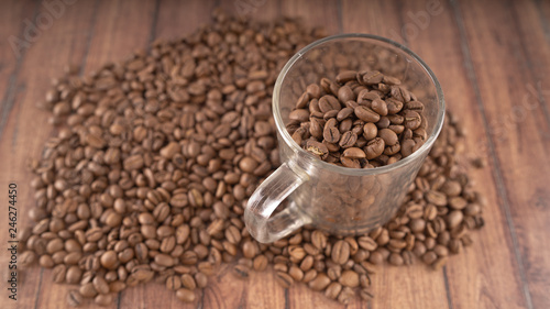 Coffee cup filled with coffee beans over a brown background