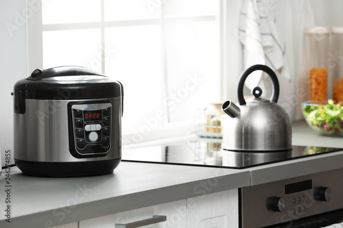 Modern electric multi cooker on kitchen countertop near stove