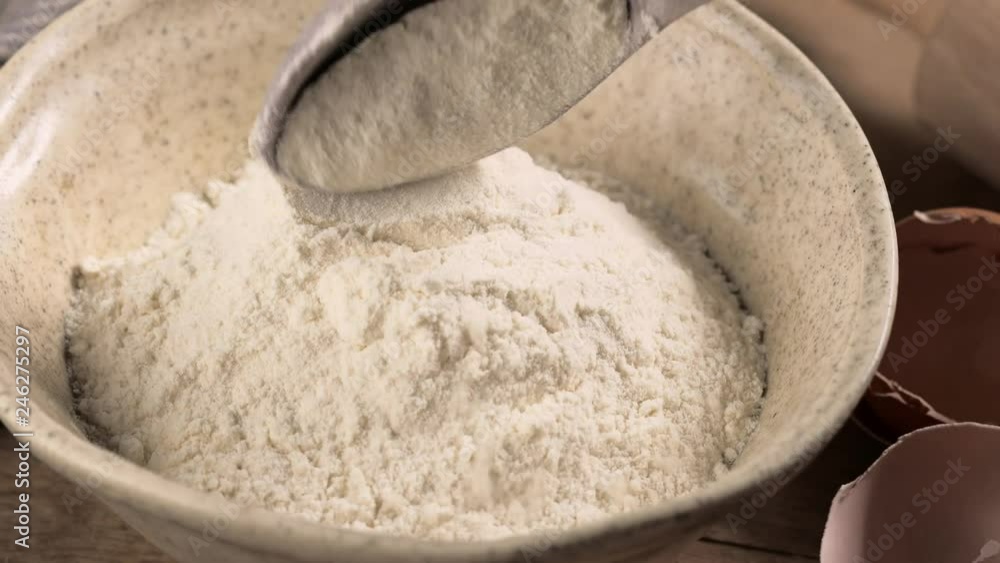 cook puts flour in a bowl with a wooden spoon for making dough cook puts flour in a bowl with a wooden spoon for making dough