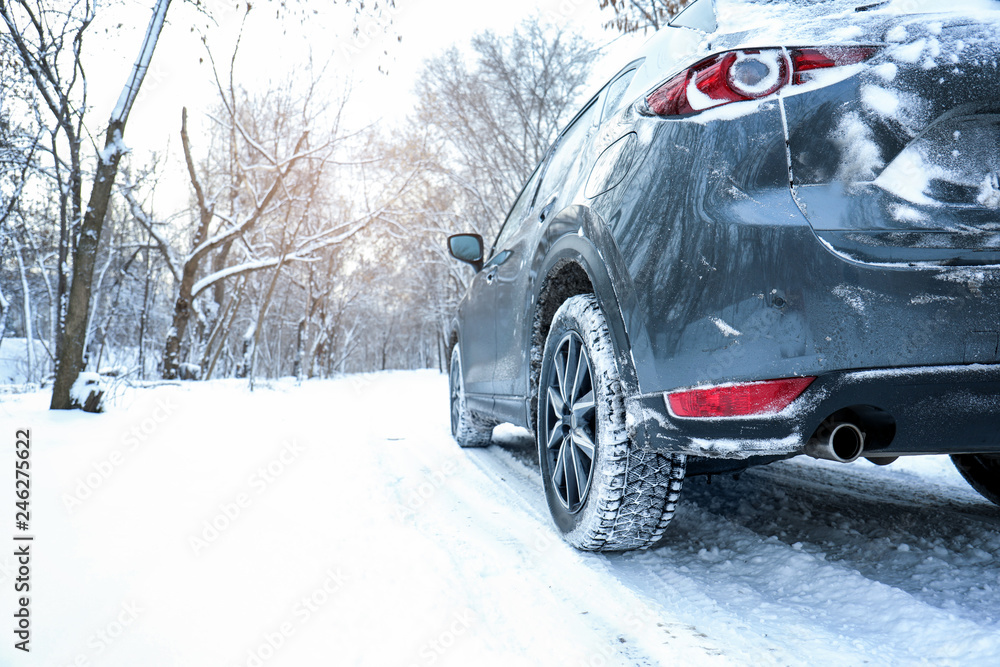 Fototapeta premium Snowy country road with car on winter day. Space for text