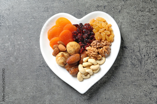 Heart shaped plate with different dried fruits and nuts on table, top view