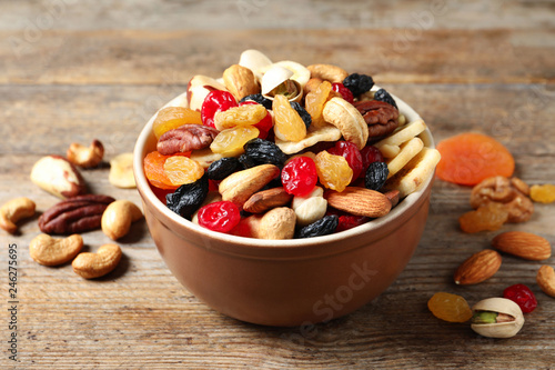 Bowl with different dried fruits and nuts on table