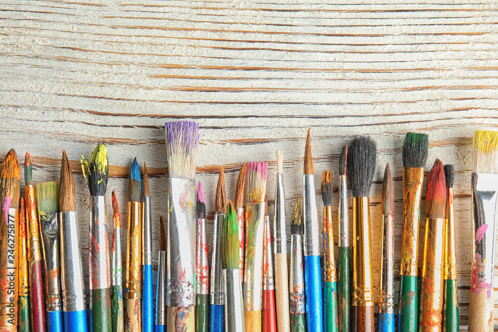 Different paint brushes on wooden background, top view with space for text Different paint brushes on wooden background, top view with space for text